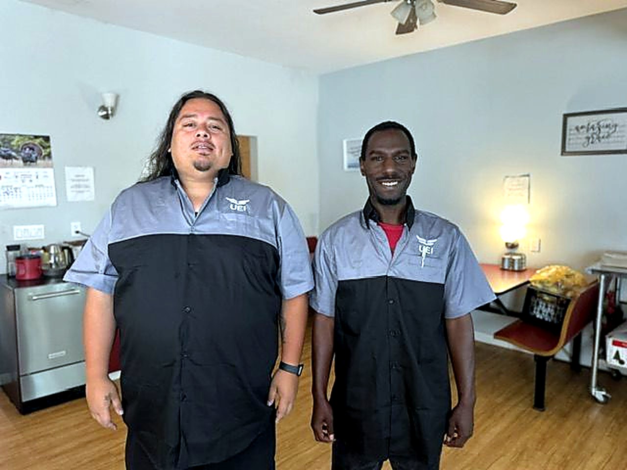 Two men in matching work-uniform shirts, ready for a day of training and work