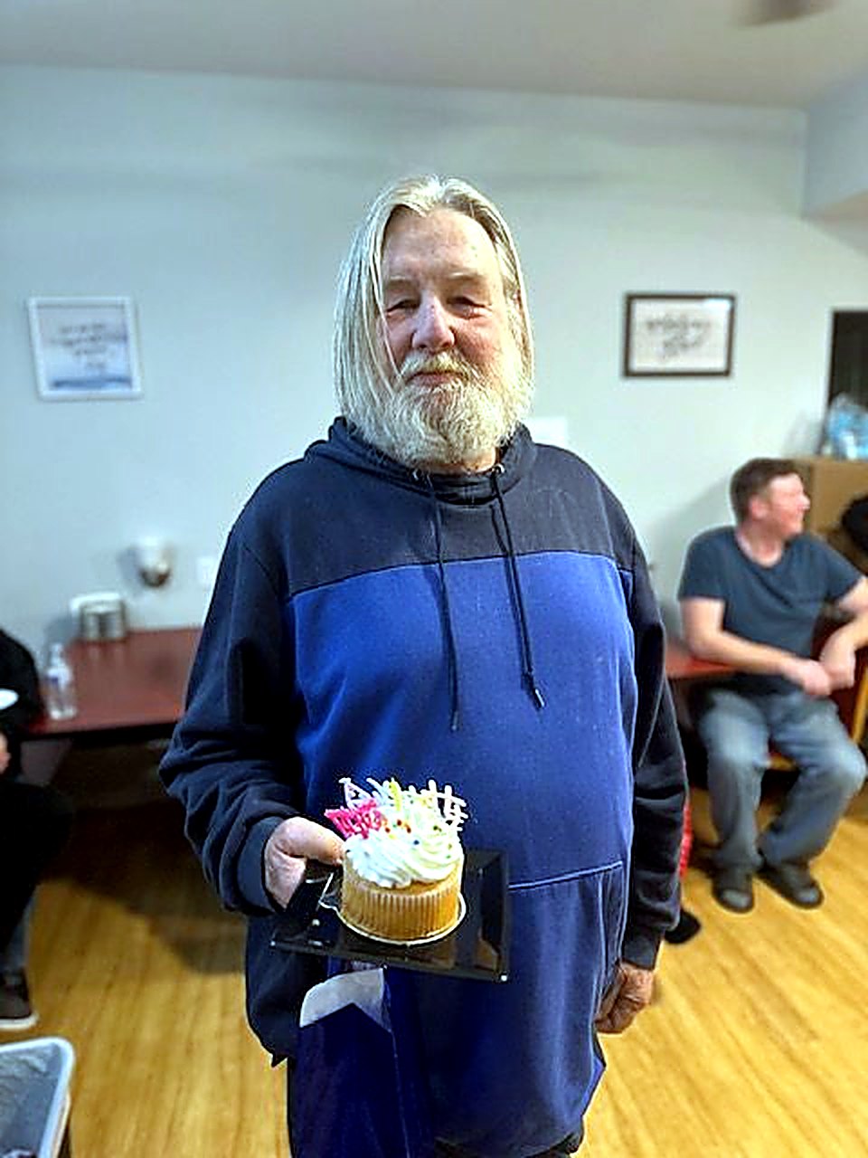 An older resident holding a birthday cupcake, smiling