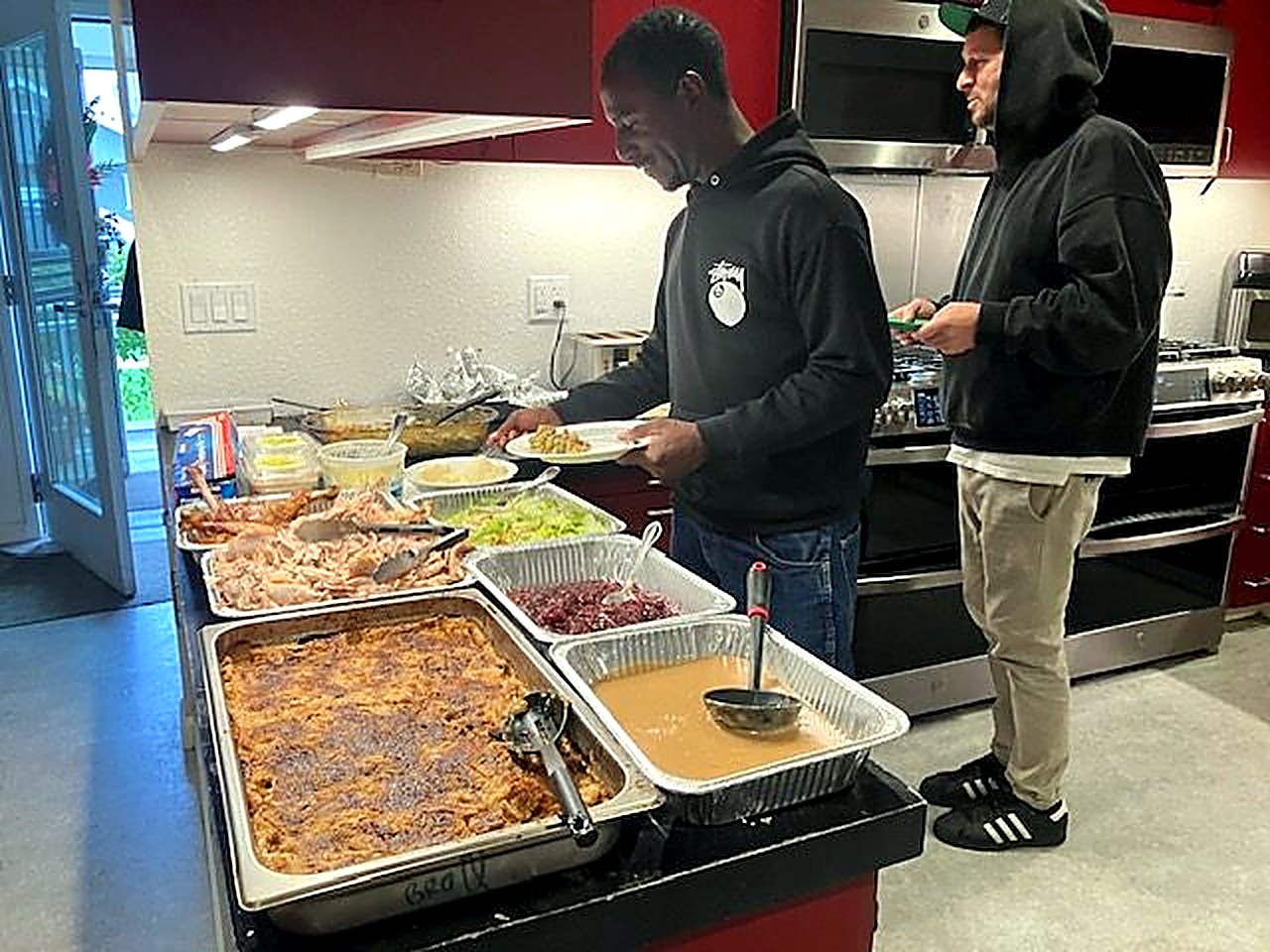 Men serving themselves from a shared holiday meal in the kitchen